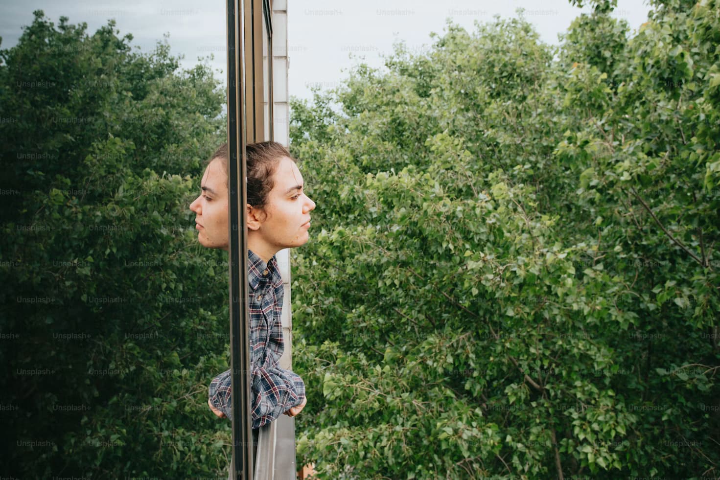 Person reflecting quietly while looking through a window